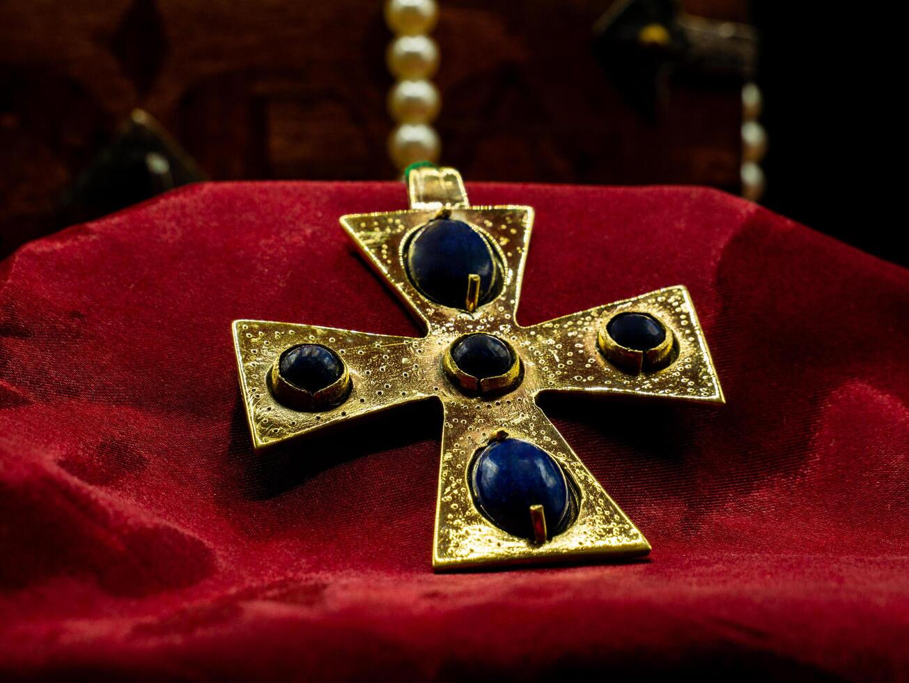 close up shot of golden jewel pendant ancient medieval set with blue gems representing a cross photo