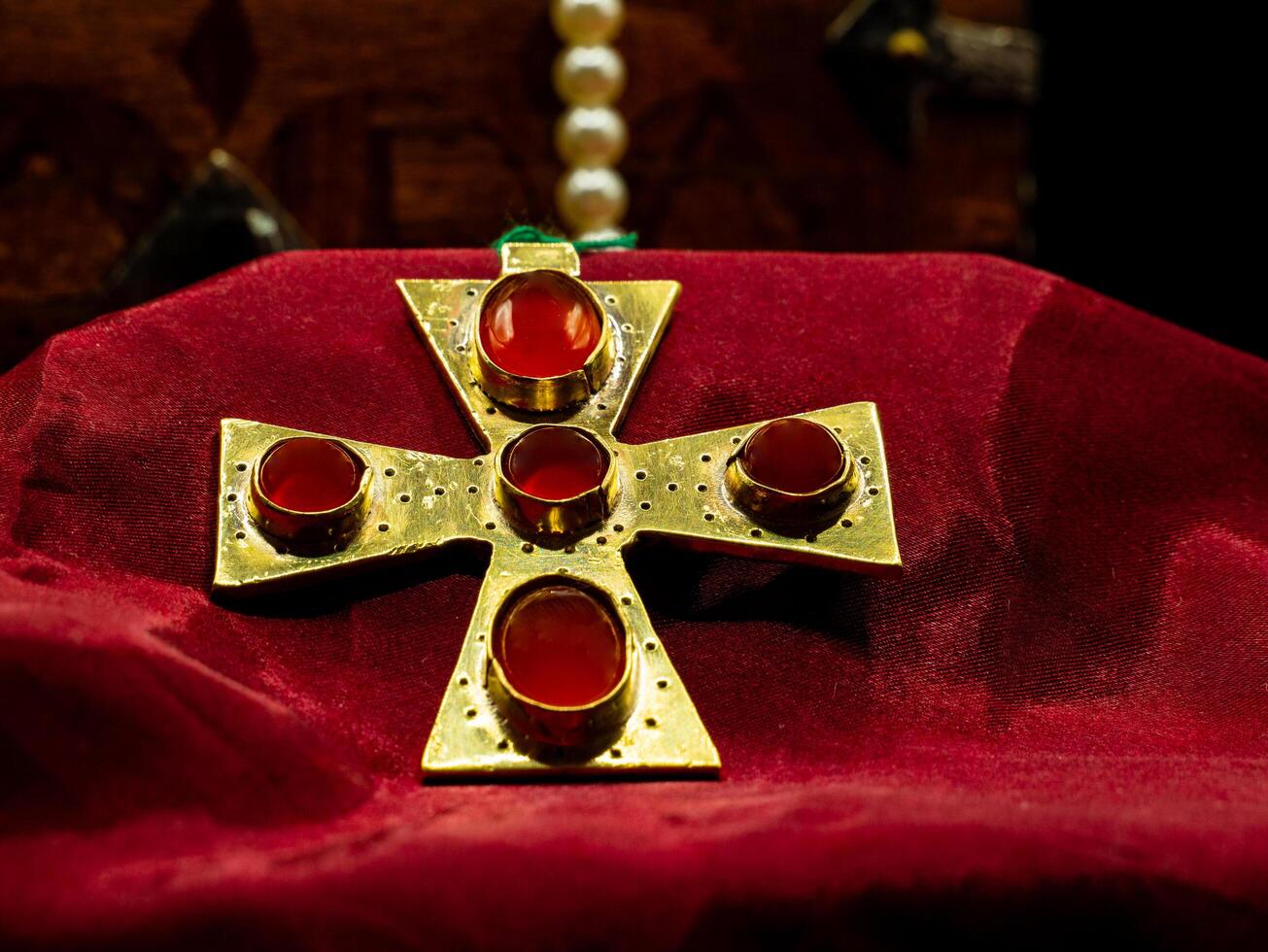 close up shot of golden jewel pendant ancient medieval set with red ruby gems representing a cross photo