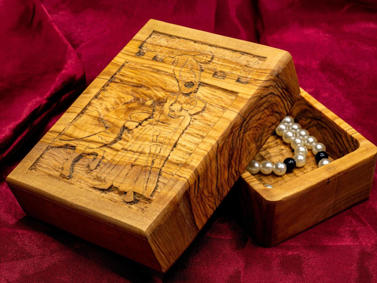 close up shot medieval wooden jewelry box engraved with a pearl necklace inside photo