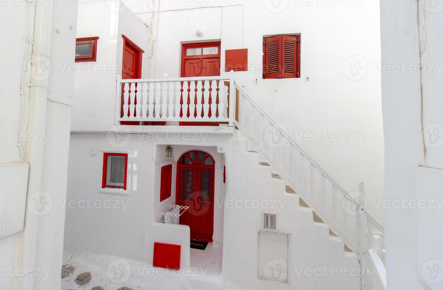 Whitewashed alley with stairs and colorful doors and windows in Mykonos, Greece. Traditional Cycladic architecture. photo
