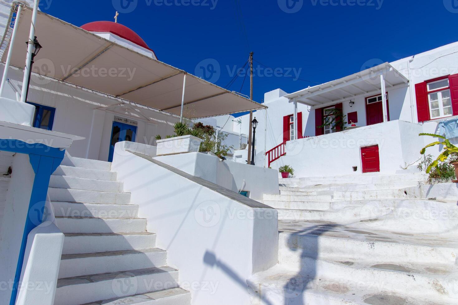 Whitewashed alley with stairs and colorful doors and windows in Mykonos, Greece. Traditional Cycladic architecture. photo