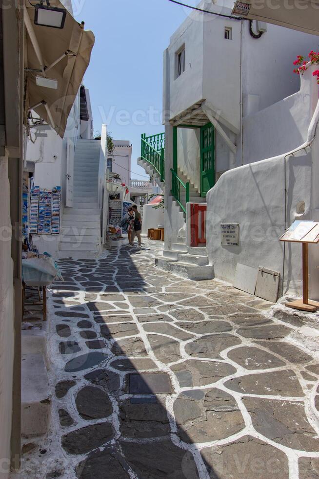 Whitewashed alley with stairs and colorful doors and windows in Mykonos, Greece. Traditional Cycladic architecture. photo