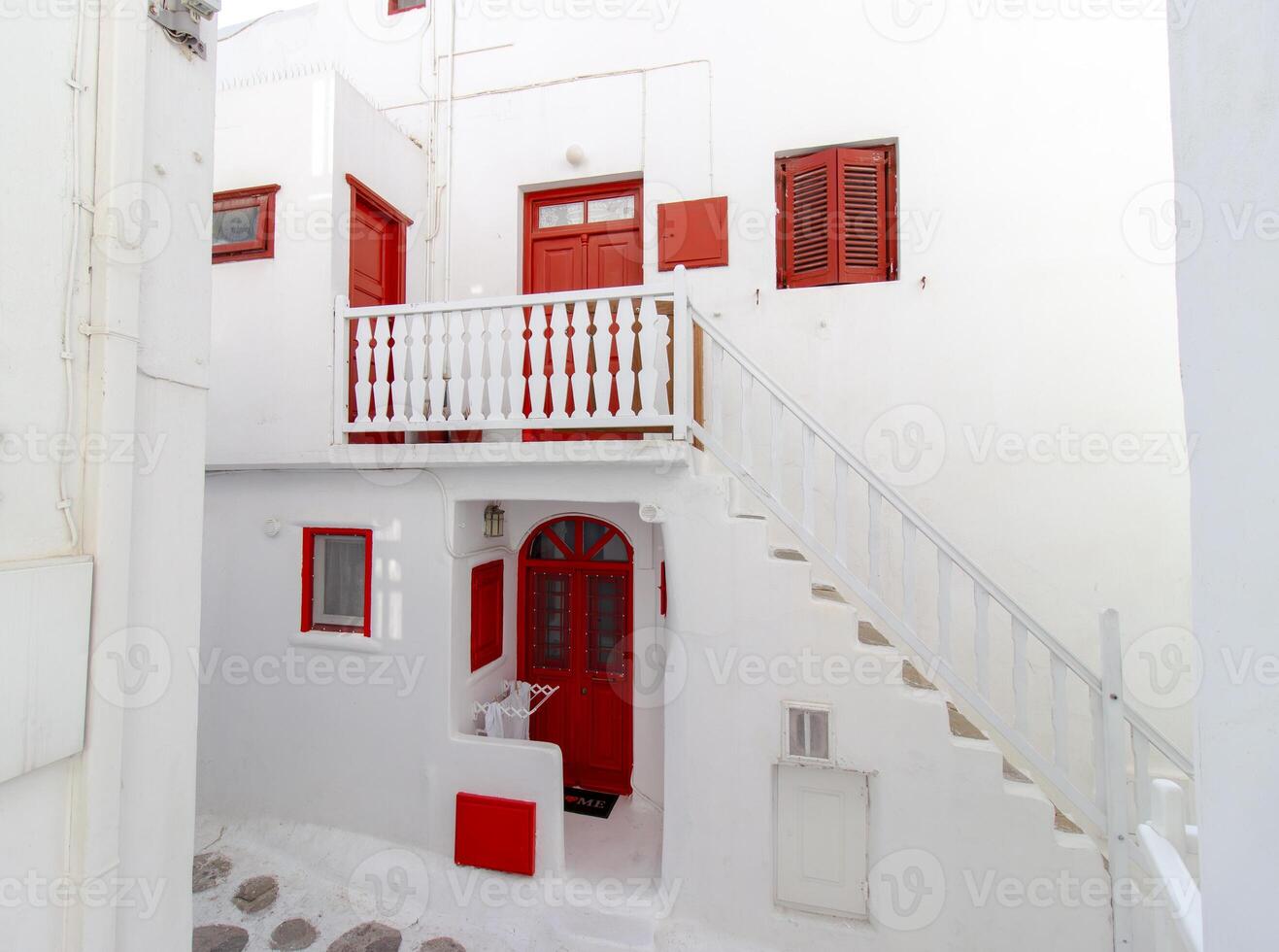 Whitewashed alley with stairs and colorful doors and windows in Mykonos, Greece. Traditional Cycladic architecture. photo