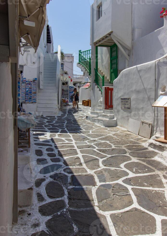 Whitewashed alley with stairs and colorful doors and windows in Mykonos, Greece. Traditional Cycladic architecture. photo