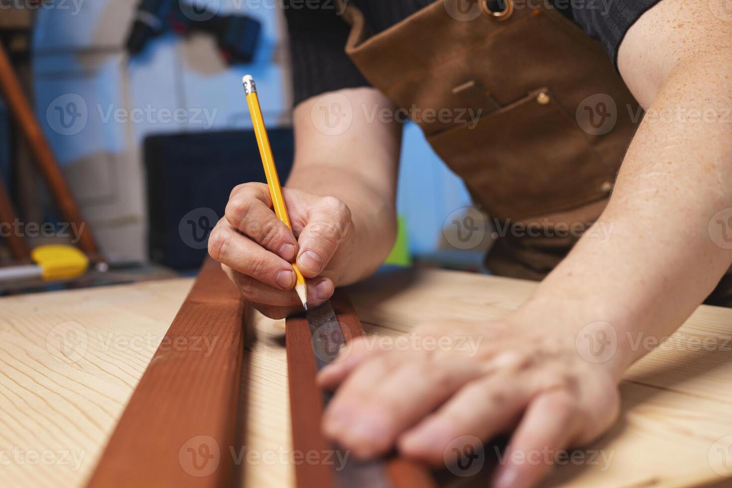 A carpenter making a mark with pencil after measuring a wooden board photo