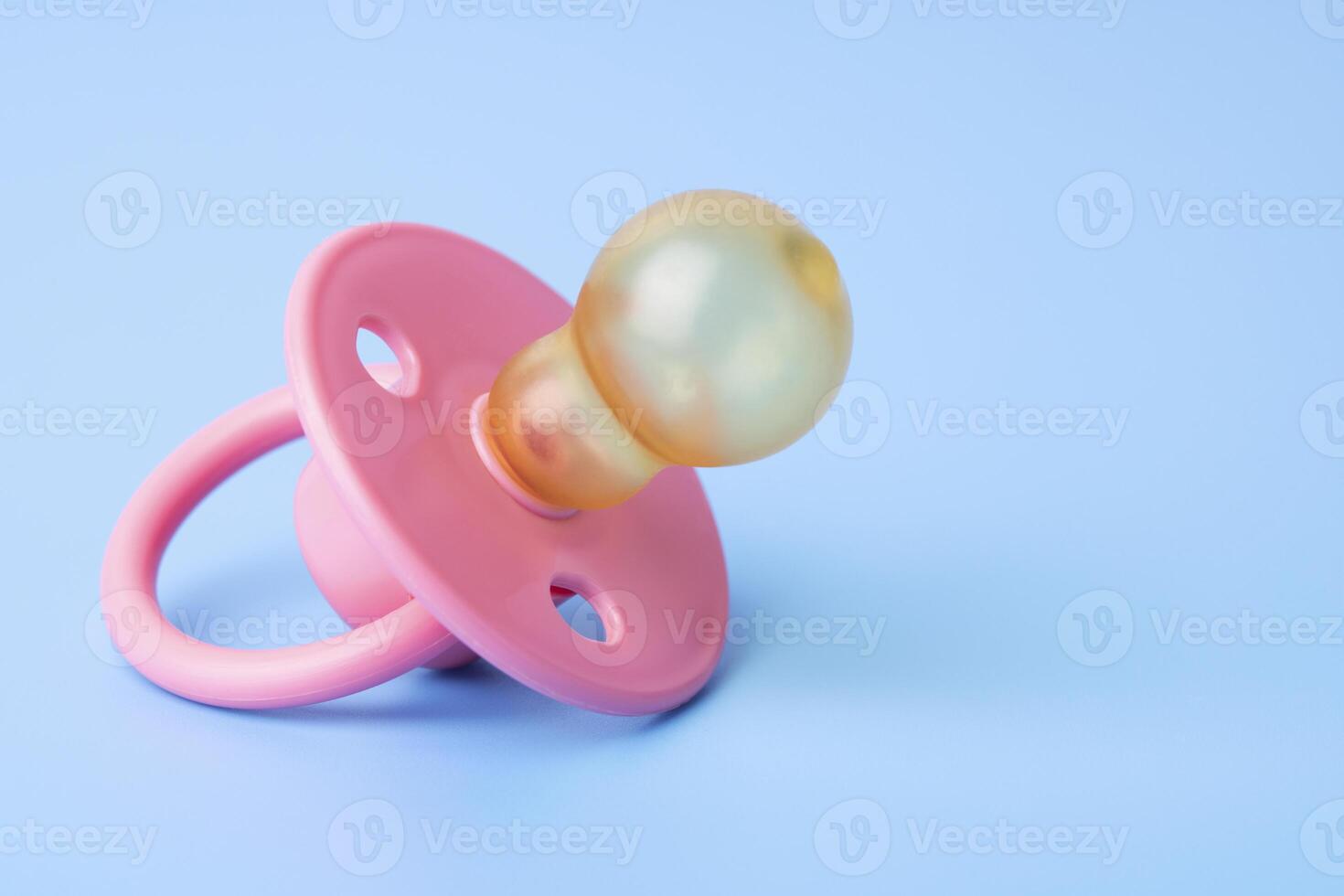 Orthodontic pacifier on a blue background. Pink baby pacifier photo