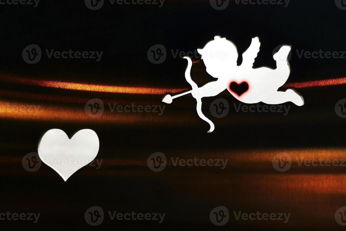 Silhouette of a cupid and a heart on the dark background photo