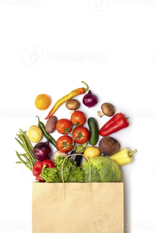 Fresh vegetables in eco friendly paper bag on white background, top view photo