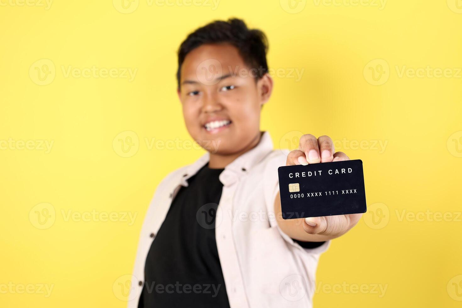 Overweight Asian Boy Holding Black Card, Isolated on Yellow Background photo