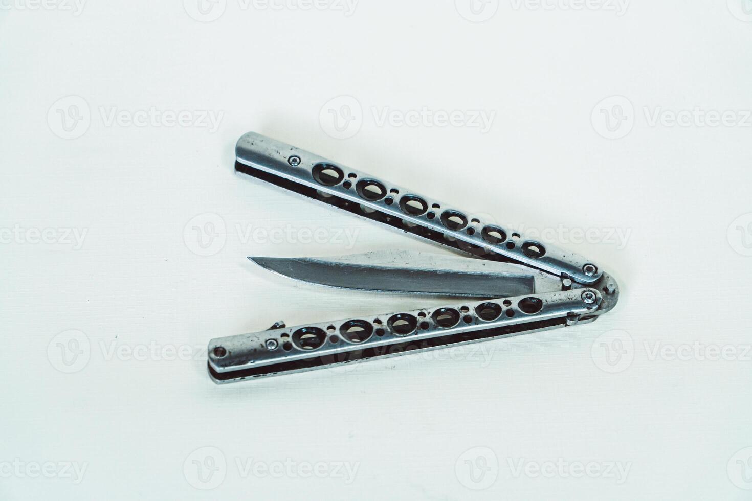 Partially open silver balisong or butterfly knife isolated on white background. Close-up of a sharp balisong knife or butterfly knife in various positions on a white background photo