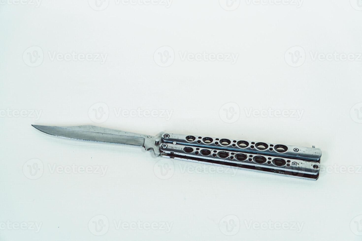 Partially open silver balisong or butterfly knife isolated on white background. Close-up of a sharp balisong knife or butterfly knife in various positions on a white background photo