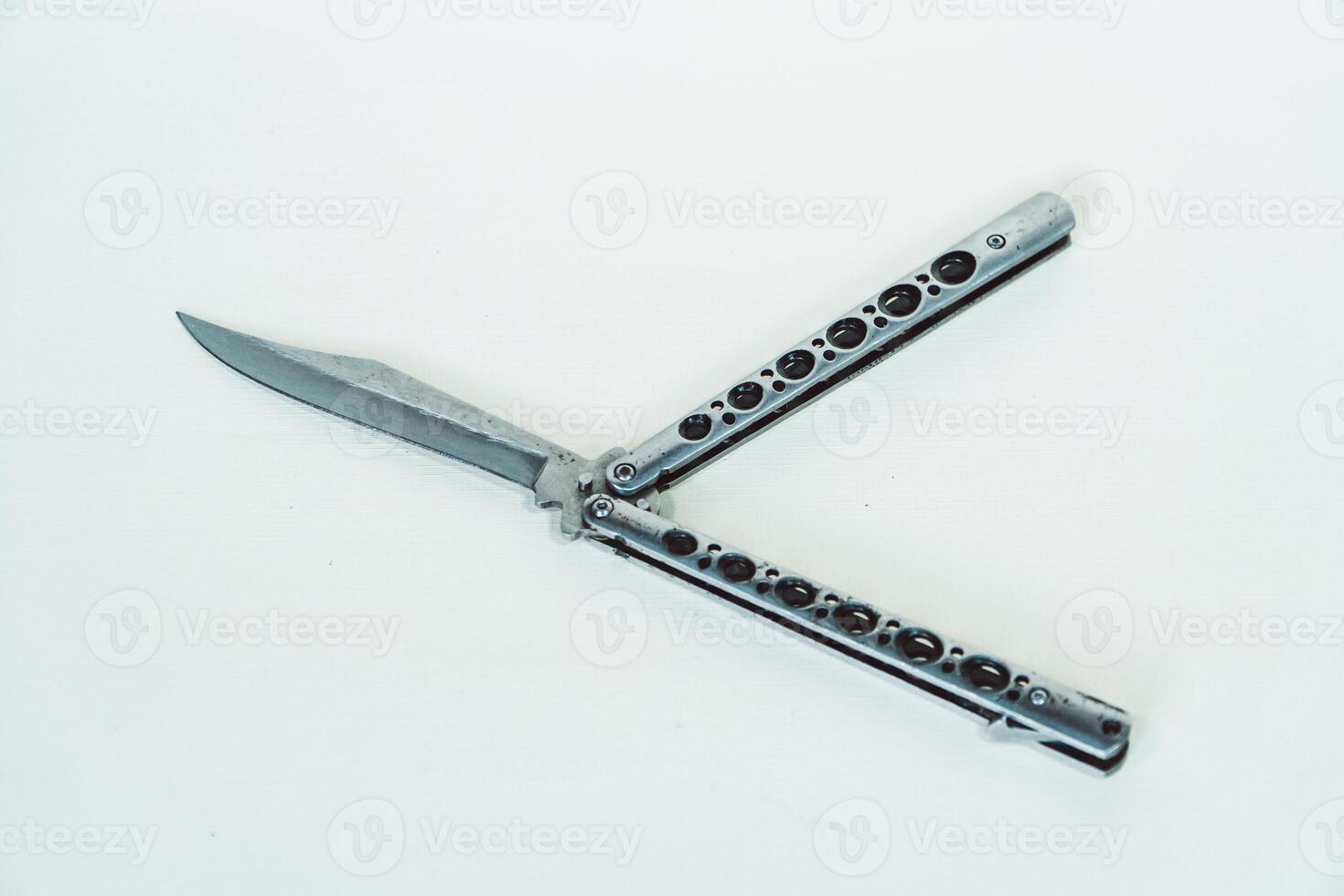 Partially open silver balisong or butterfly knife isolated on white background. Close-up of a sharp balisong knife or butterfly knife in various positions on a white background photo