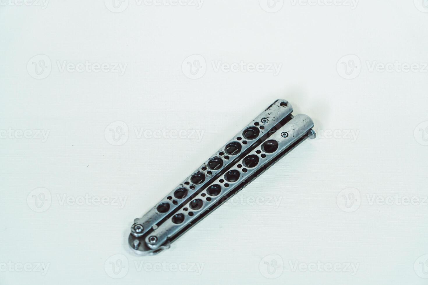 Partially open silver balisong or butterfly knife isolated on white background. Close-up of a sharp balisong knife or butterfly knife in various positions on a white background photo