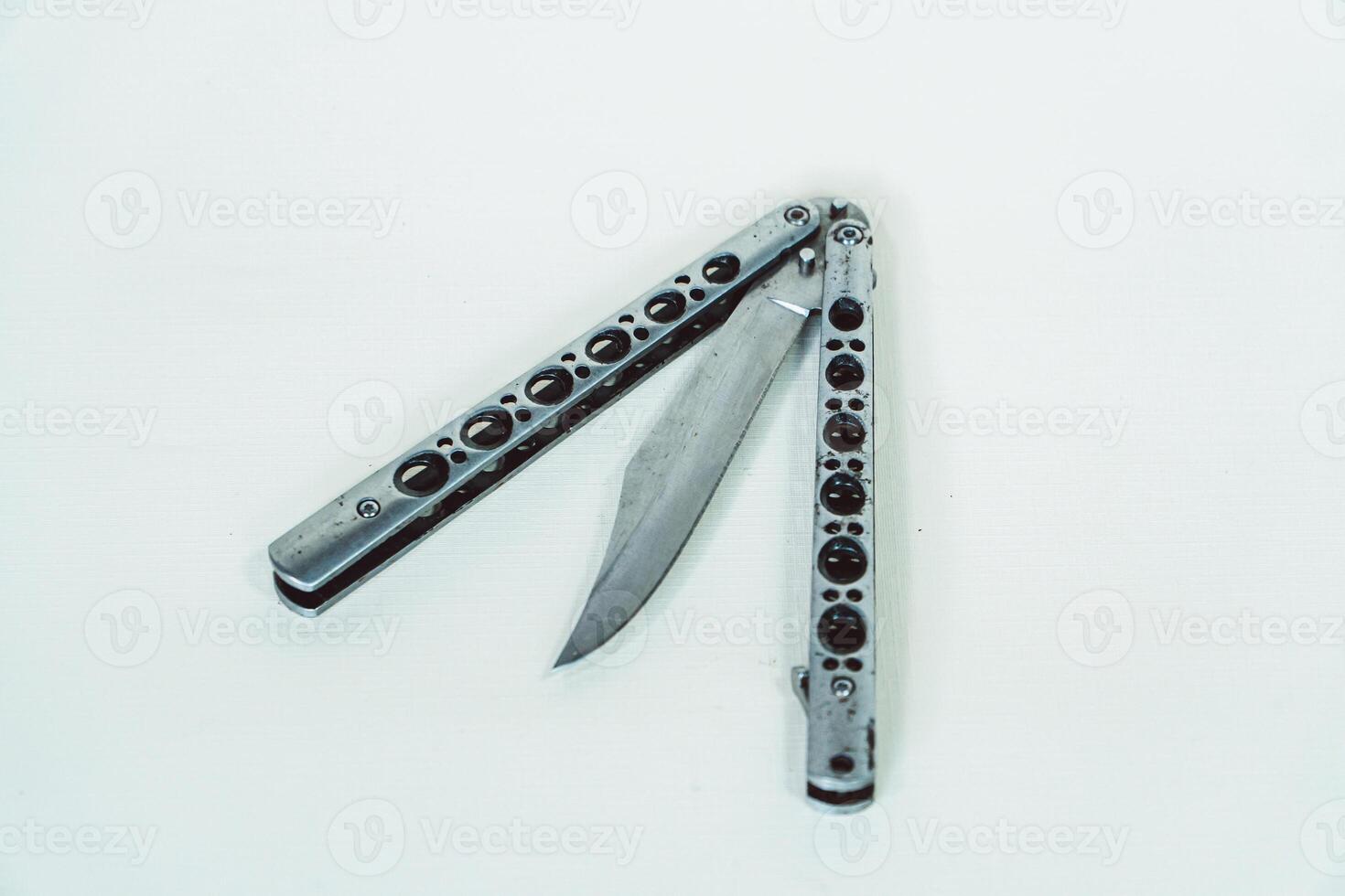 Partially open silver balisong or butterfly knife isolated on white background. Close-up of a sharp balisong knife or butterfly knife in various positions on a white background photo