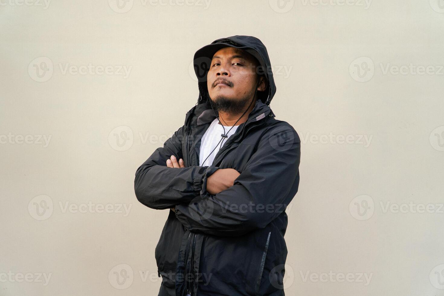 Portrait of Asian man wearing adventure clothes and doing various poses. Macho and smiling adult man wearing white shirt and jacket with hood isolated on beige background photo