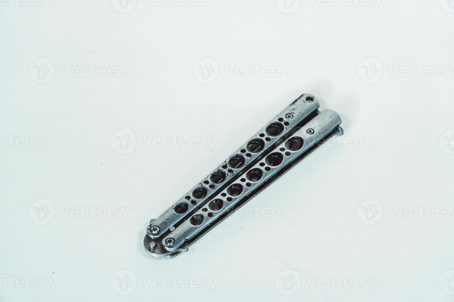 Partially open silver balisong or butterfly knife isolated on white background. Close-up of a sharp balisong knife or butterfly knife in various positions on a white background photo