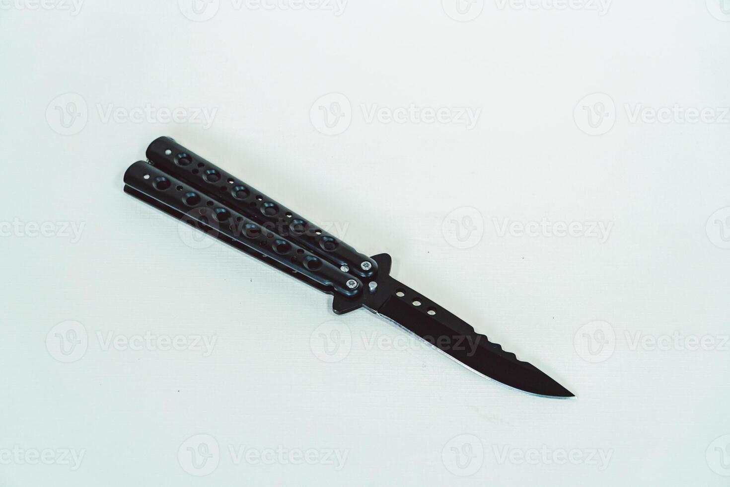 Partially open matte black balisong or butterfly knife isolated on white background. Close-up of a sharp balisong knife or butterfly knife in various positions on a white background photo