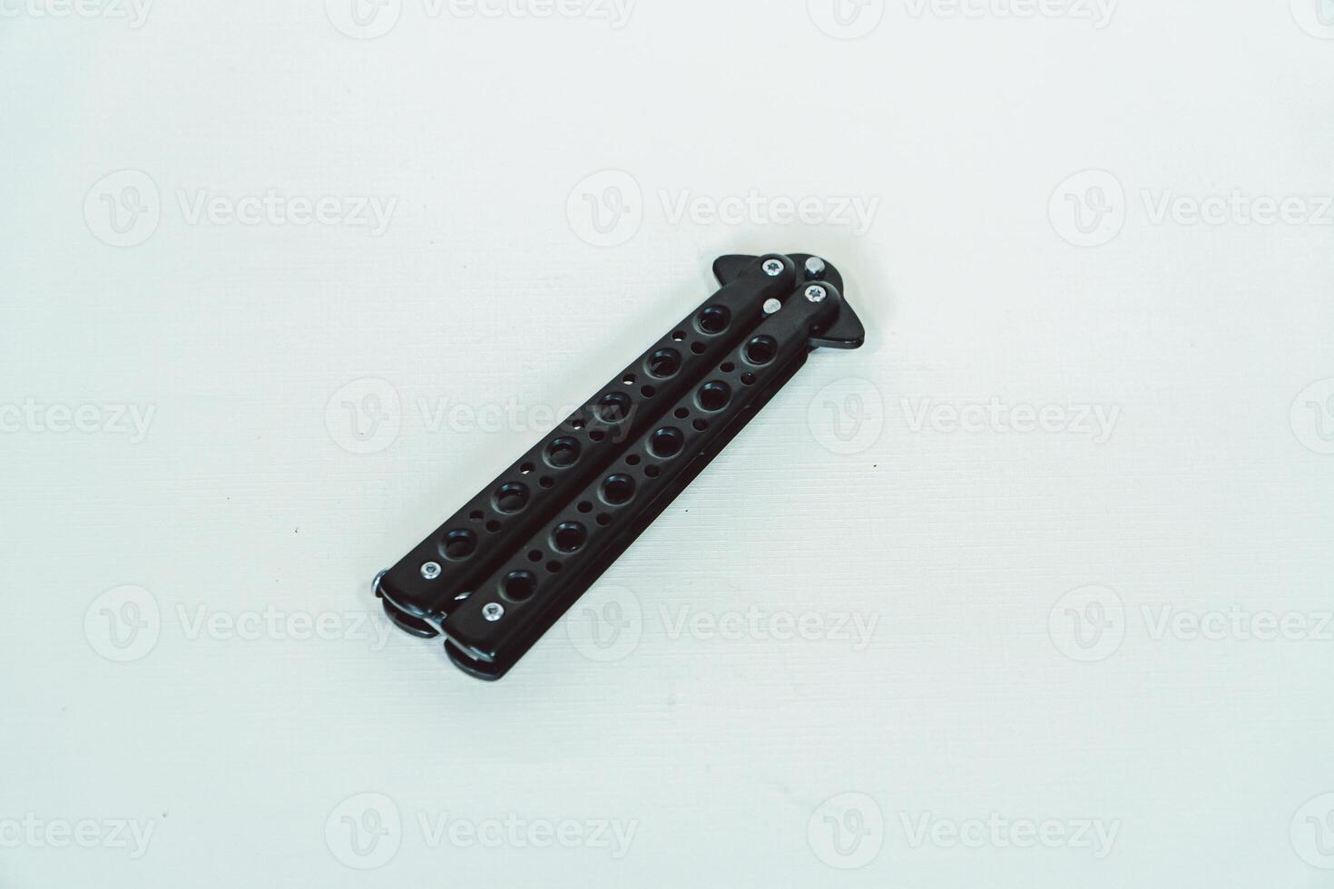 Partially open matte black balisong or butterfly knife isolated on white background. Close-up of a sharp balisong knife or butterfly knife in various positions on a white background photo