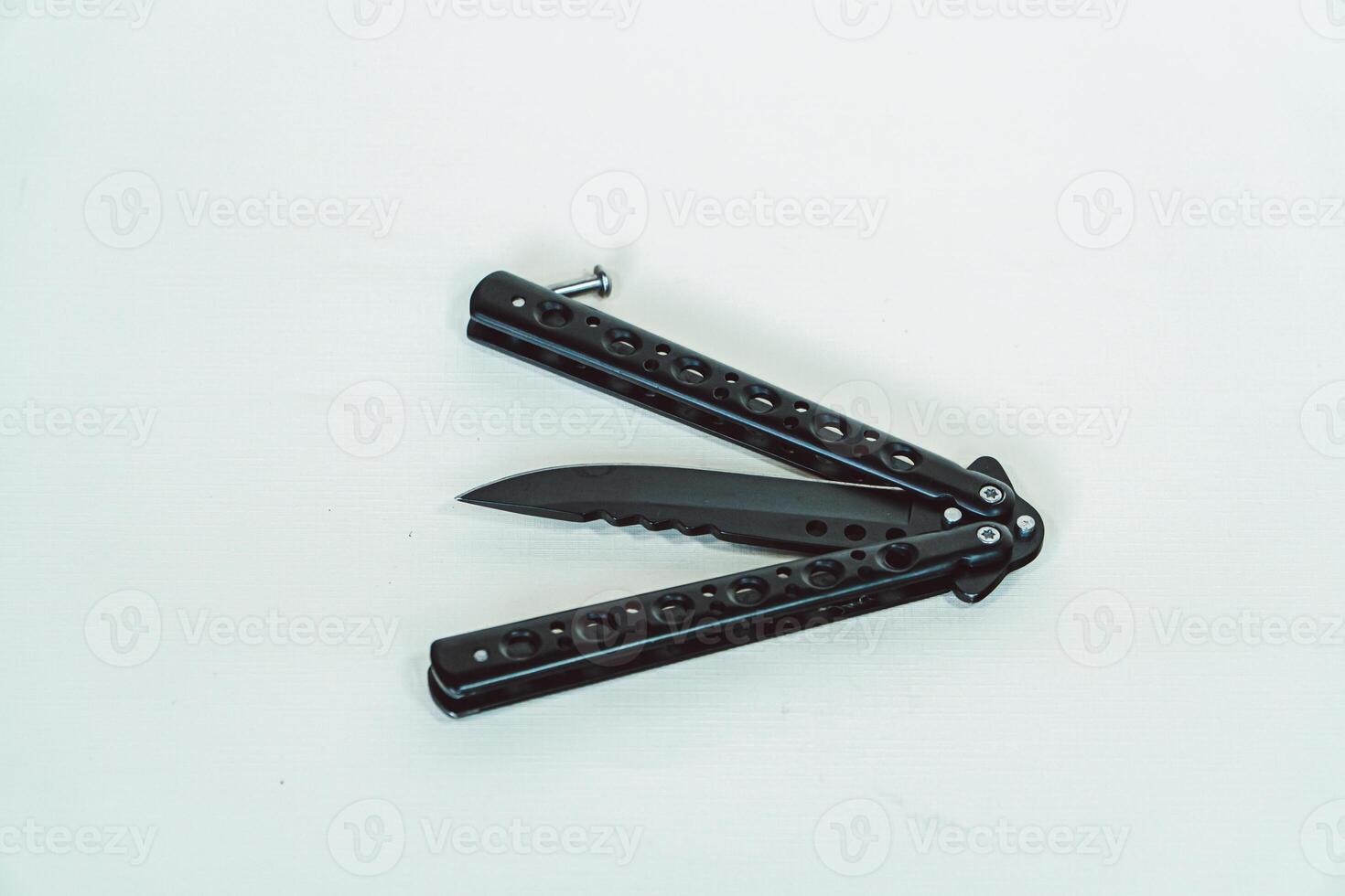 Partially open matte black balisong or butterfly knife isolated on white background. Close-up of a sharp balisong knife or butterfly knife in various positions on a white background photo