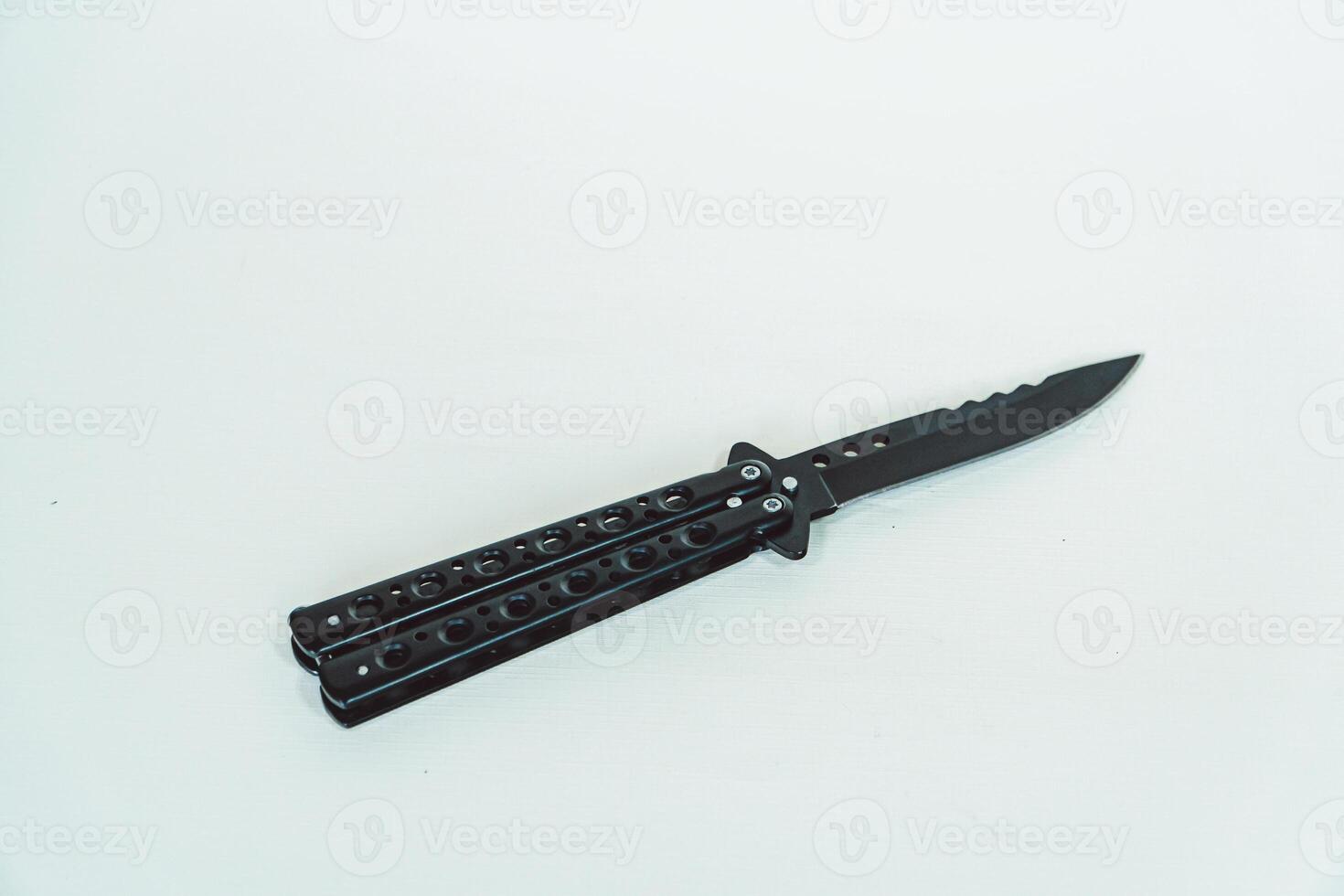 Partially open matte black balisong or butterfly knife isolated on white background. Close-up of a sharp balisong knife or butterfly knife in various positions on a white background photo