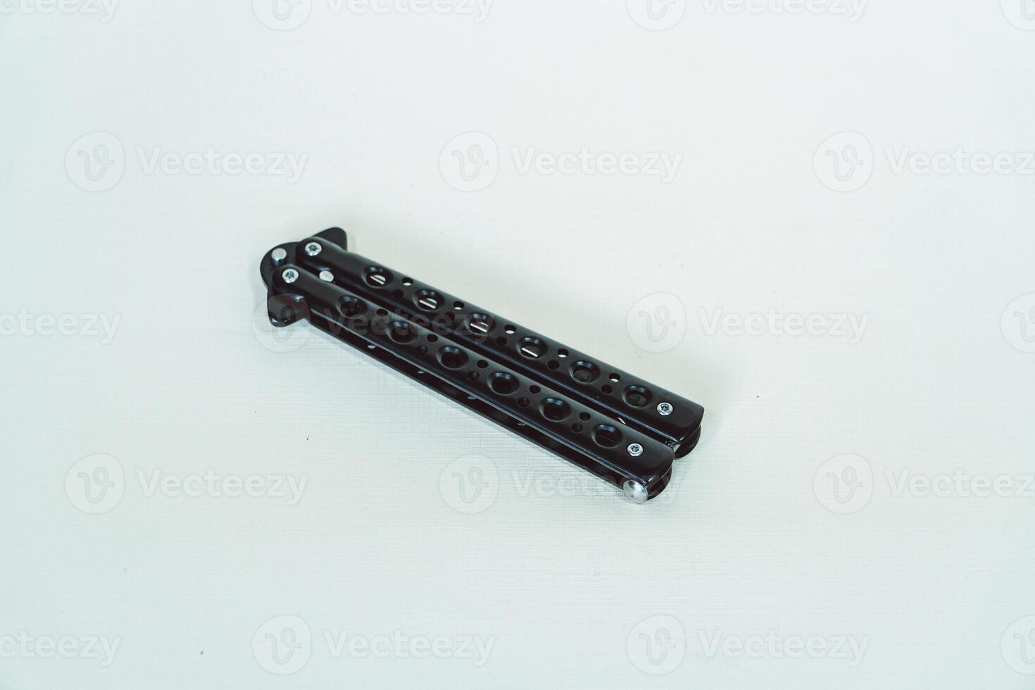 Partially open matte black balisong or butterfly knife isolated on white background. Close-up of a sharp balisong knife or butterfly knife in various positions on a white background photo