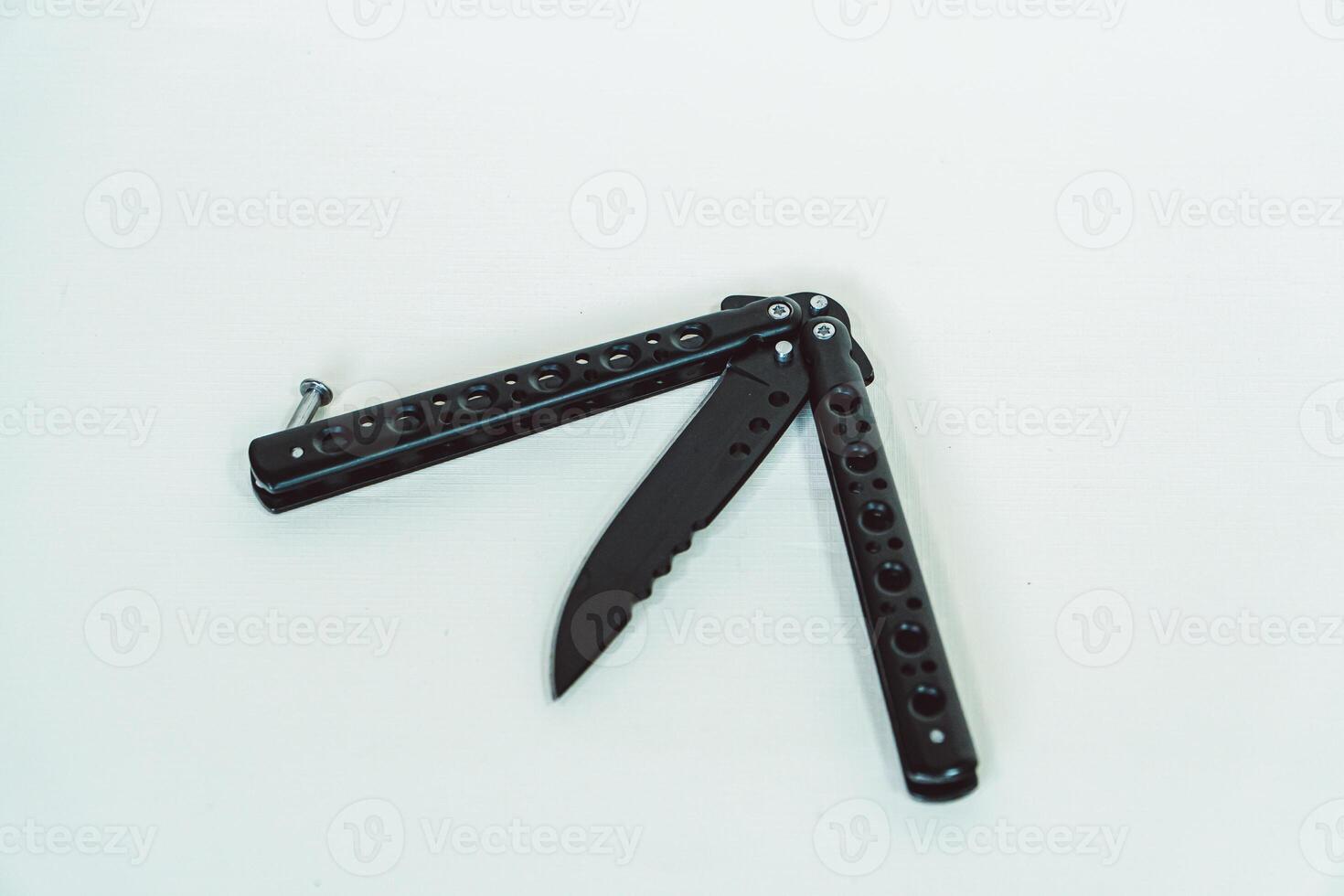 Partially open matte black balisong or butterfly knife isolated on white background. Close-up of a sharp balisong knife or butterfly knife in various positions on a white background photo