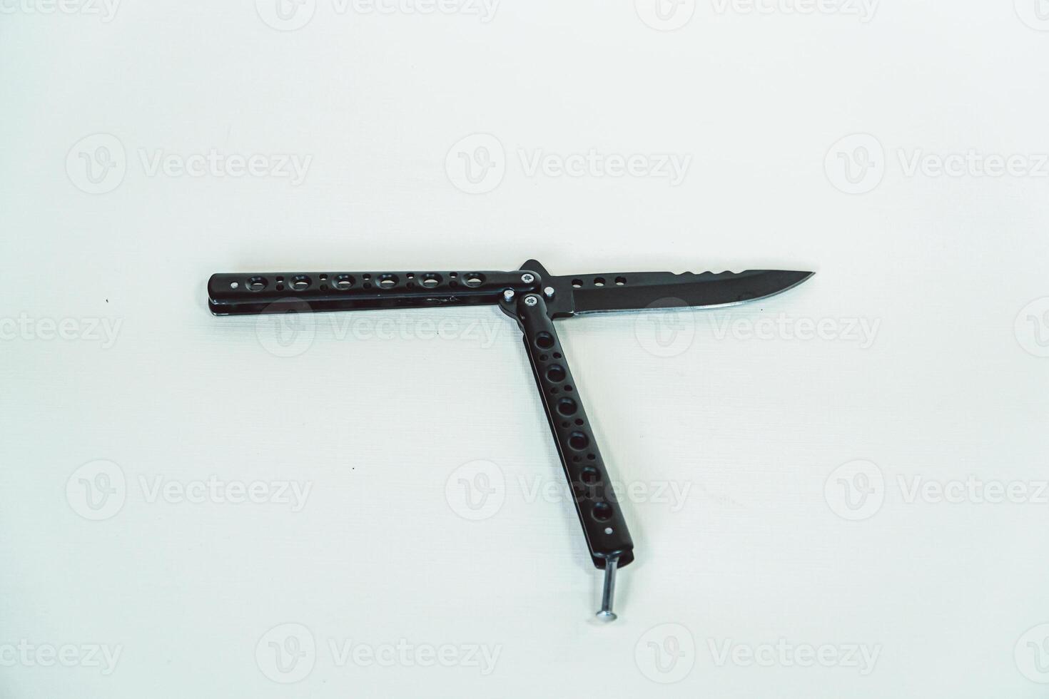 Partially open matte black balisong or butterfly knife isolated on white background. Close-up of a sharp balisong knife or butterfly knife in various positions on a white background photo