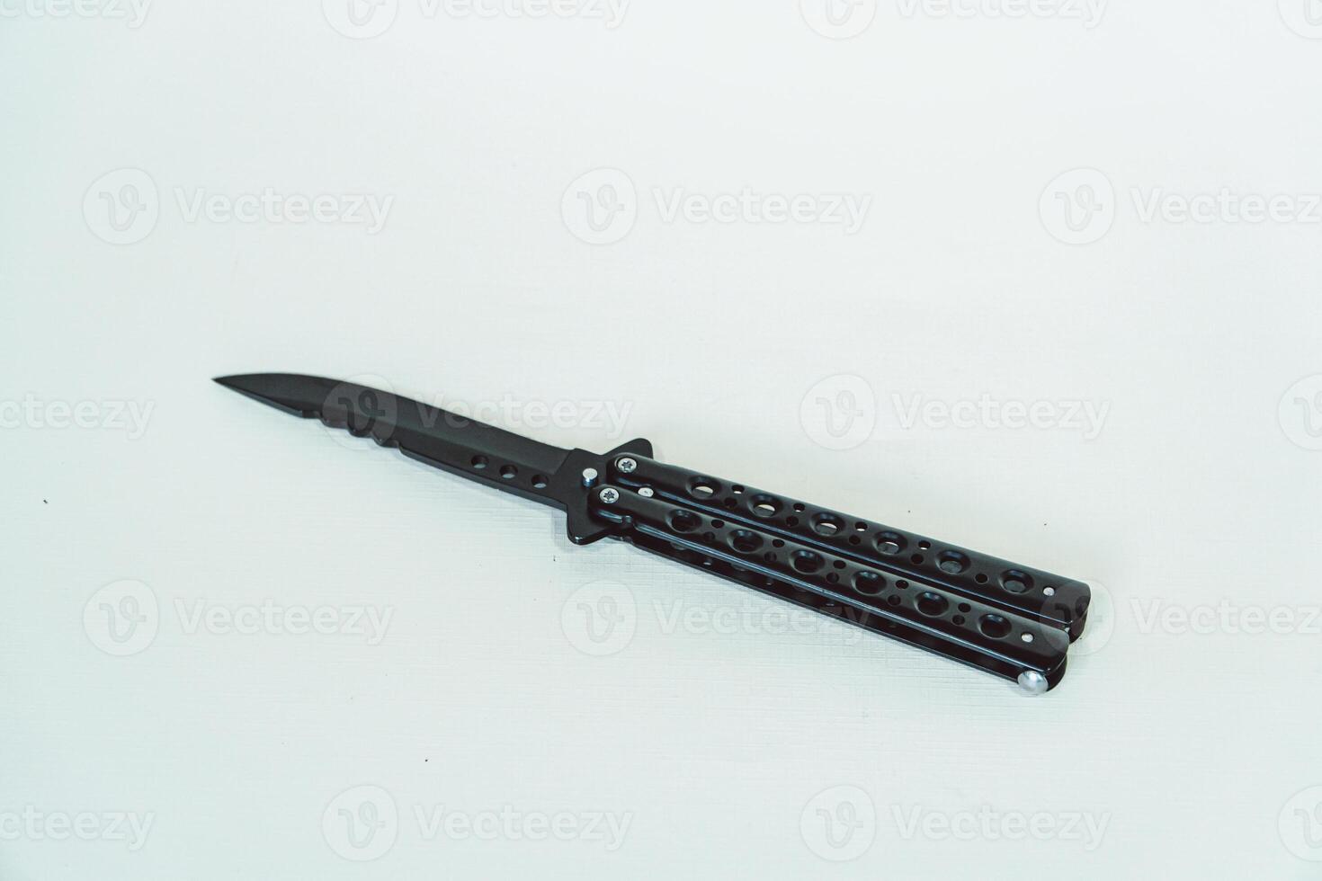 Partially open matte black balisong or butterfly knife isolated on white background. Close-up of a sharp balisong knife or butterfly knife in various positions on a white background photo
