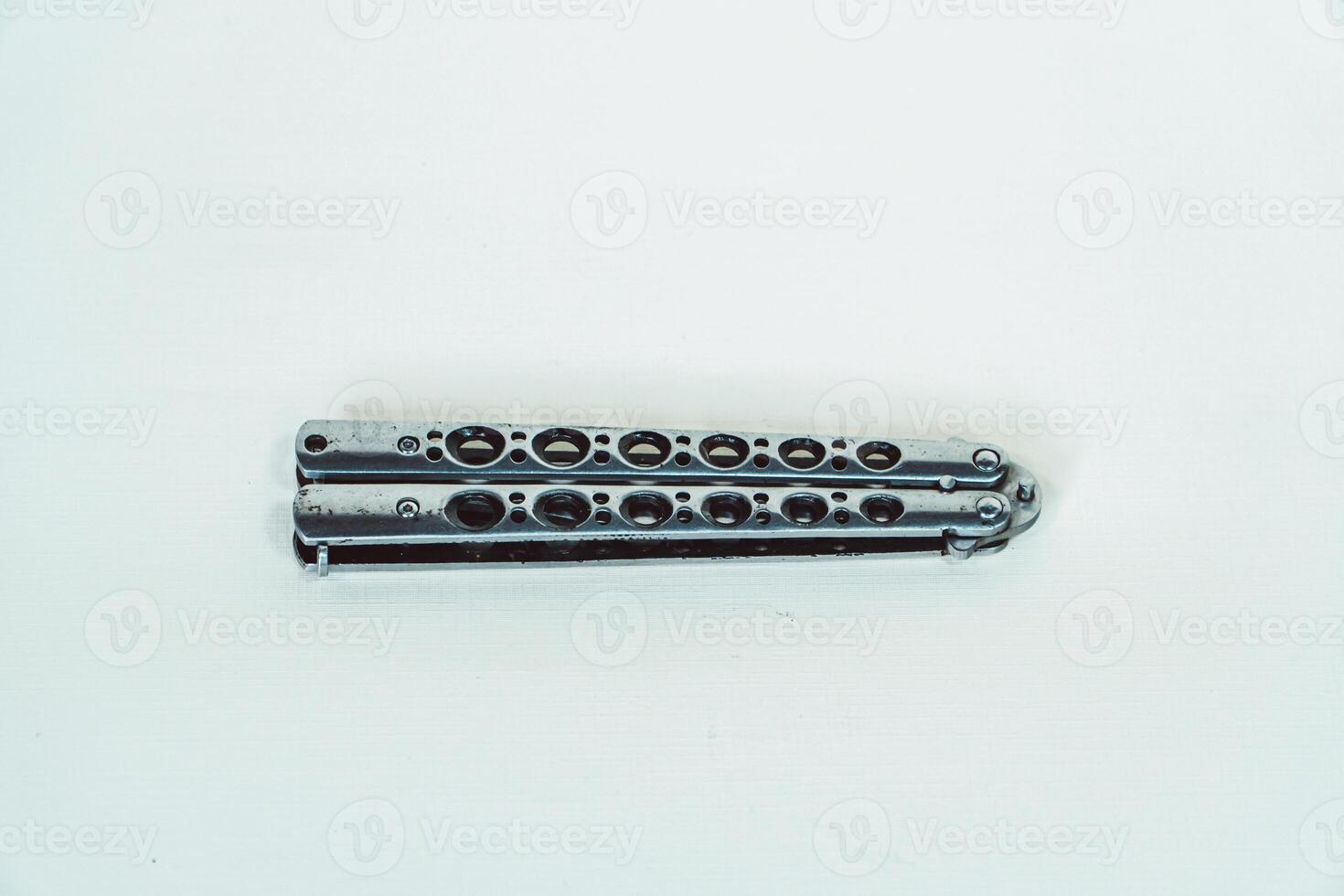 Partially open silver balisong or butterfly knife isolated on white background. Close-up of a sharp balisong knife or butterfly knife in various positions on a white background photo