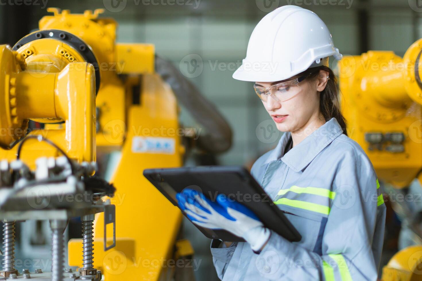 Engineer woman working in advance machine factory. Female worker engineering staff work checking robot arm in assembly plant with tablet photo