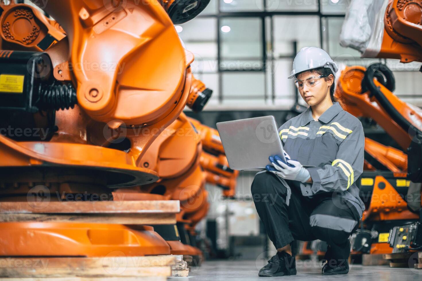 Engineer woman working in advance robotic machine factory. Indian female engineering staff work software update robot arm in assembly plant photo