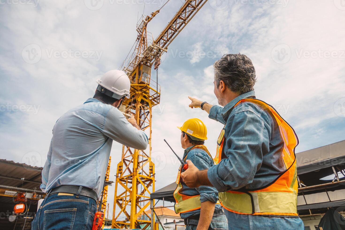 Professional construction engineer workers team working together control operating Crane tower at building project construction site. photo