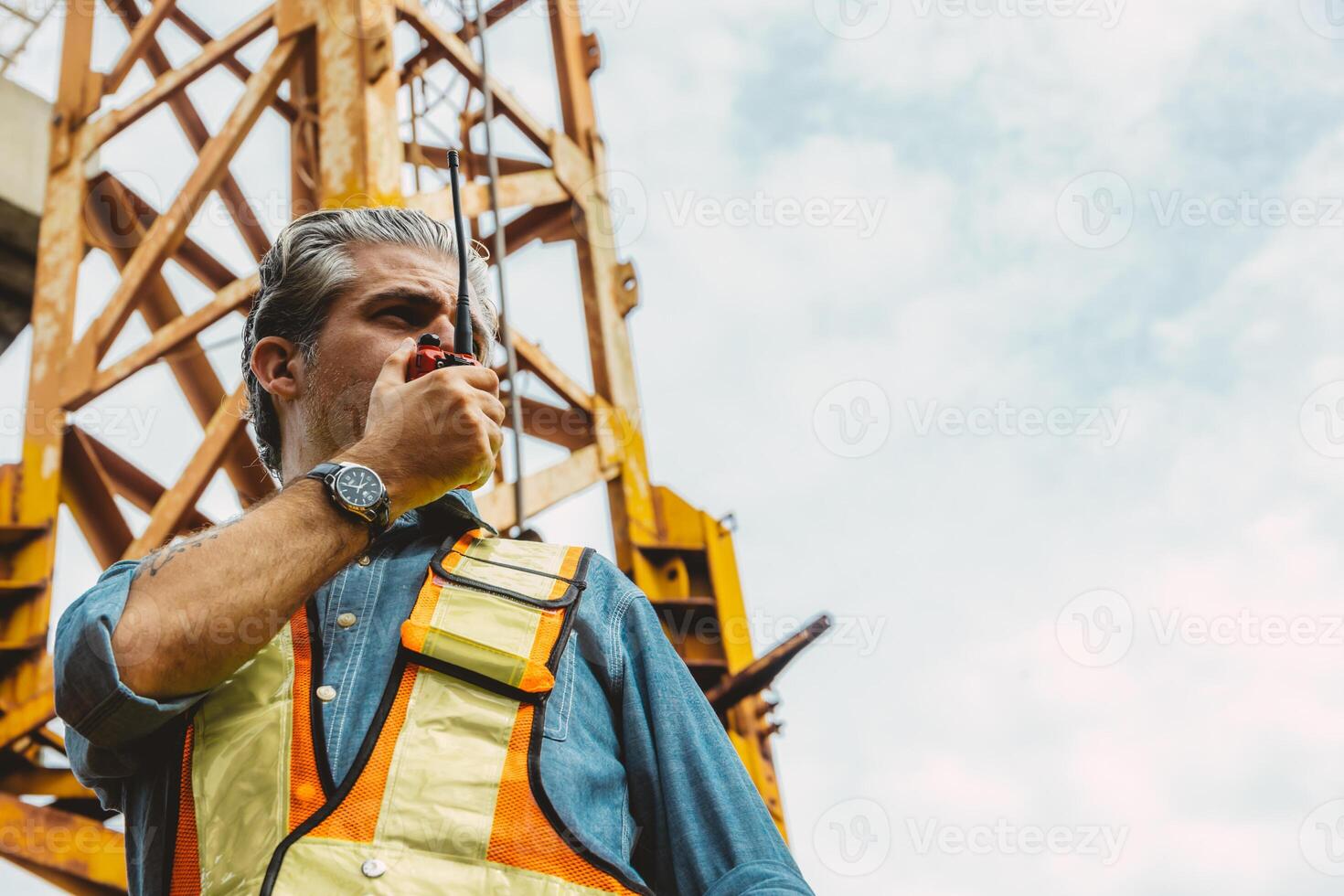 Italian worker engineer construction site control radio operation. Foreman operate crane tower working order by walkie talkie. photo