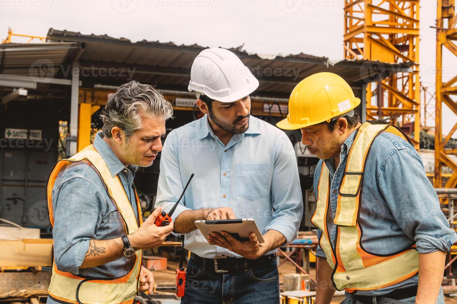 Professional construction engineer workers team working cooperate together consulting looking at tablet screen at project building construction site. photo