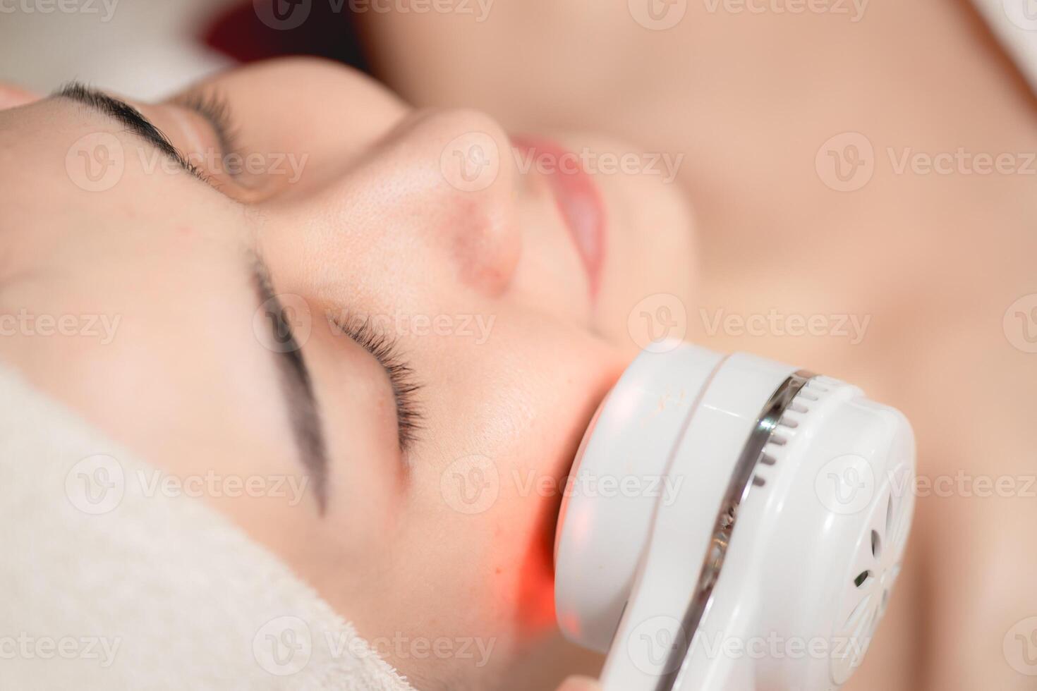 Facial cosmetic using Ultrasonic Laser Skin Glow Treatment equipment process. Young women face skin spa technology. photo