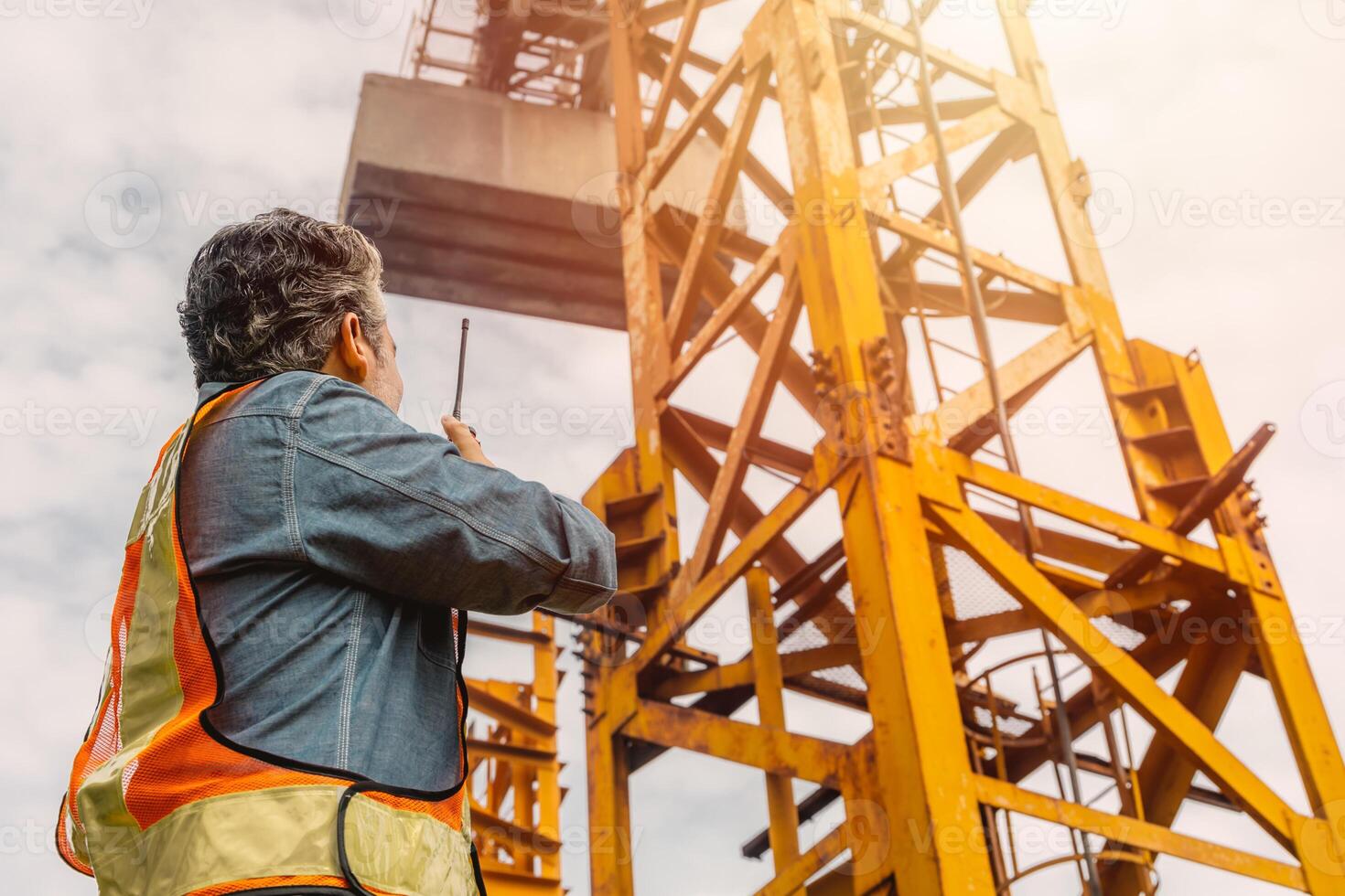 Construction engineer worker construction site radio control operation. Foreman operate tower crane working order by walkie talkie. photo