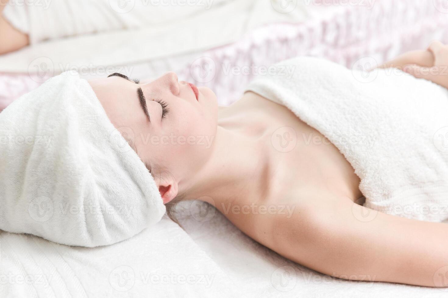 Woman Relaxing at Spa Treatment with Towel Wrapped Around Her Head photo