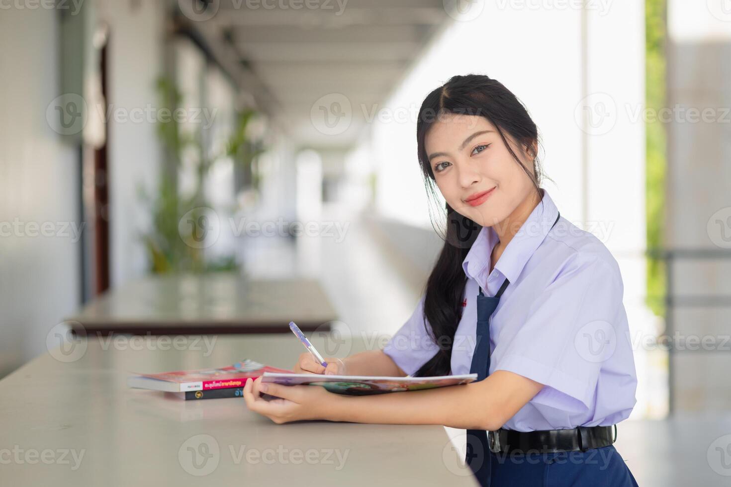 portrait asian school uniform teen girl sitting study homework. young girl learning education. photo