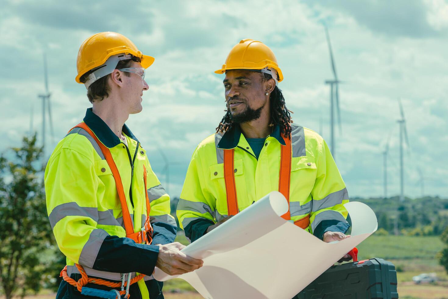 Engineer team mix black and white male workers with floor plan at Wind Turbines field working survey at wind electricity generator farm field outdoor. photo