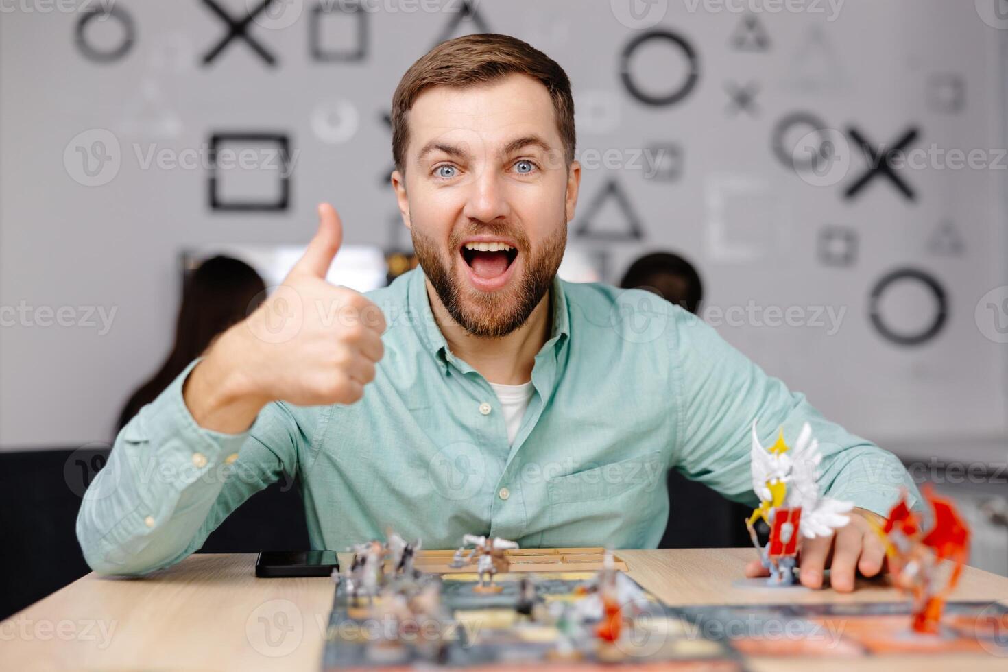 Man with board game piece while practicing strategy in home alone. A man plays a board game with cards and figures, expressing different emotions photo