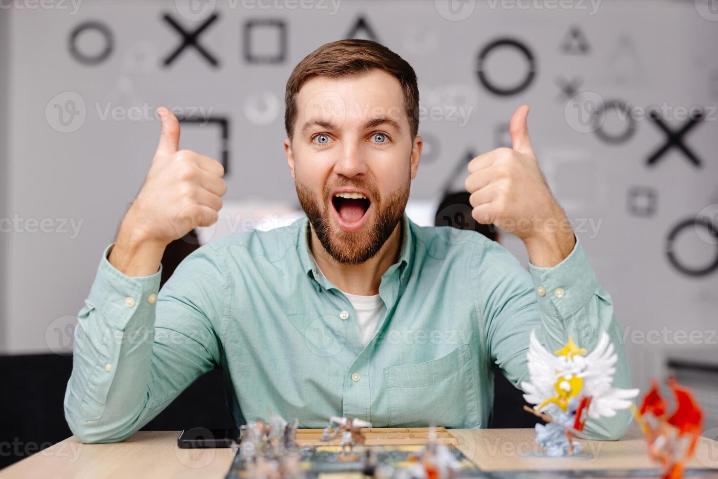 Man with board game piece while practicing strategy in home alone. A man plays a board game with cards and figures, expressing different emotions photo