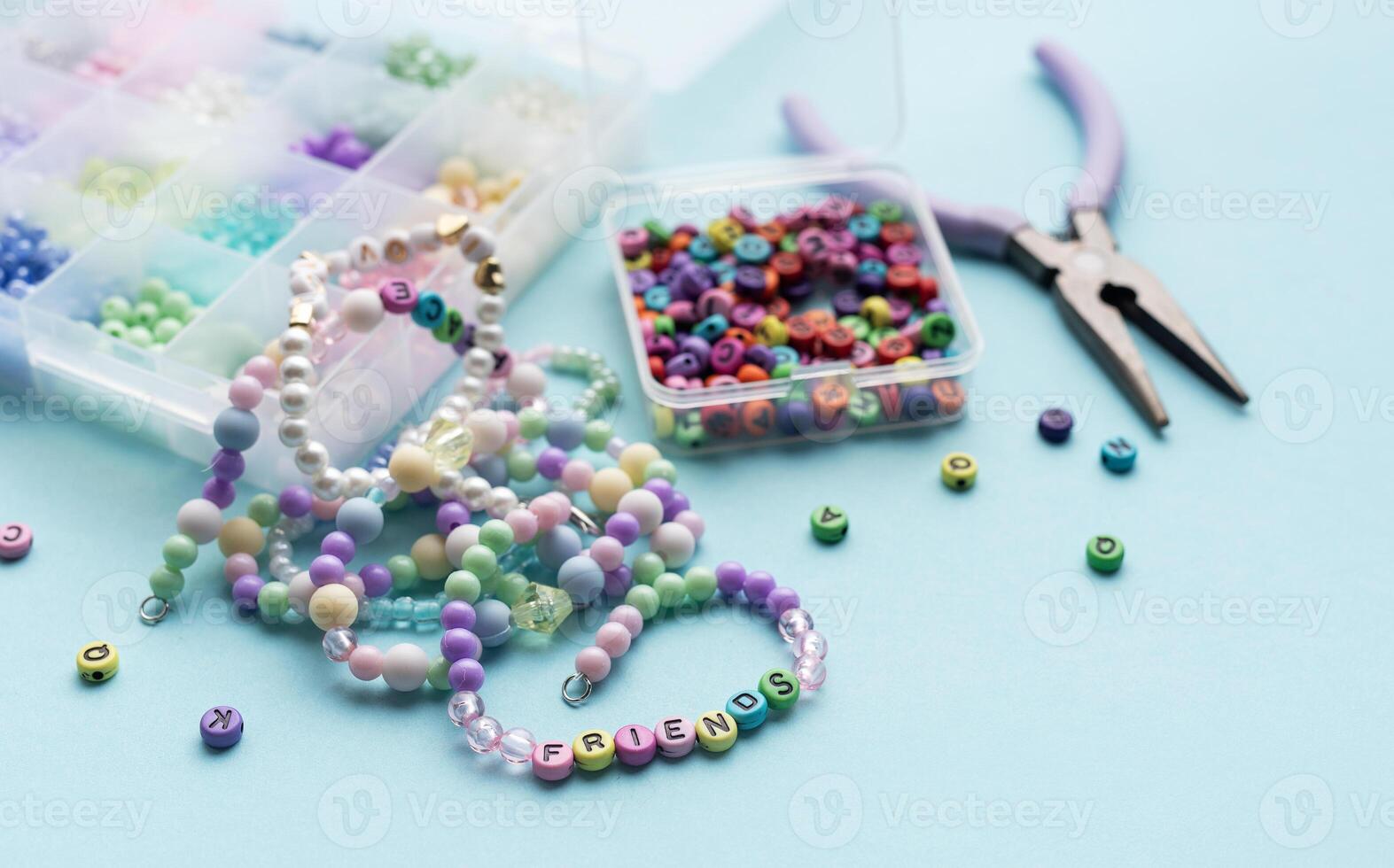 Colorful beads and pliers creating friendship bracelets on blue background photo
