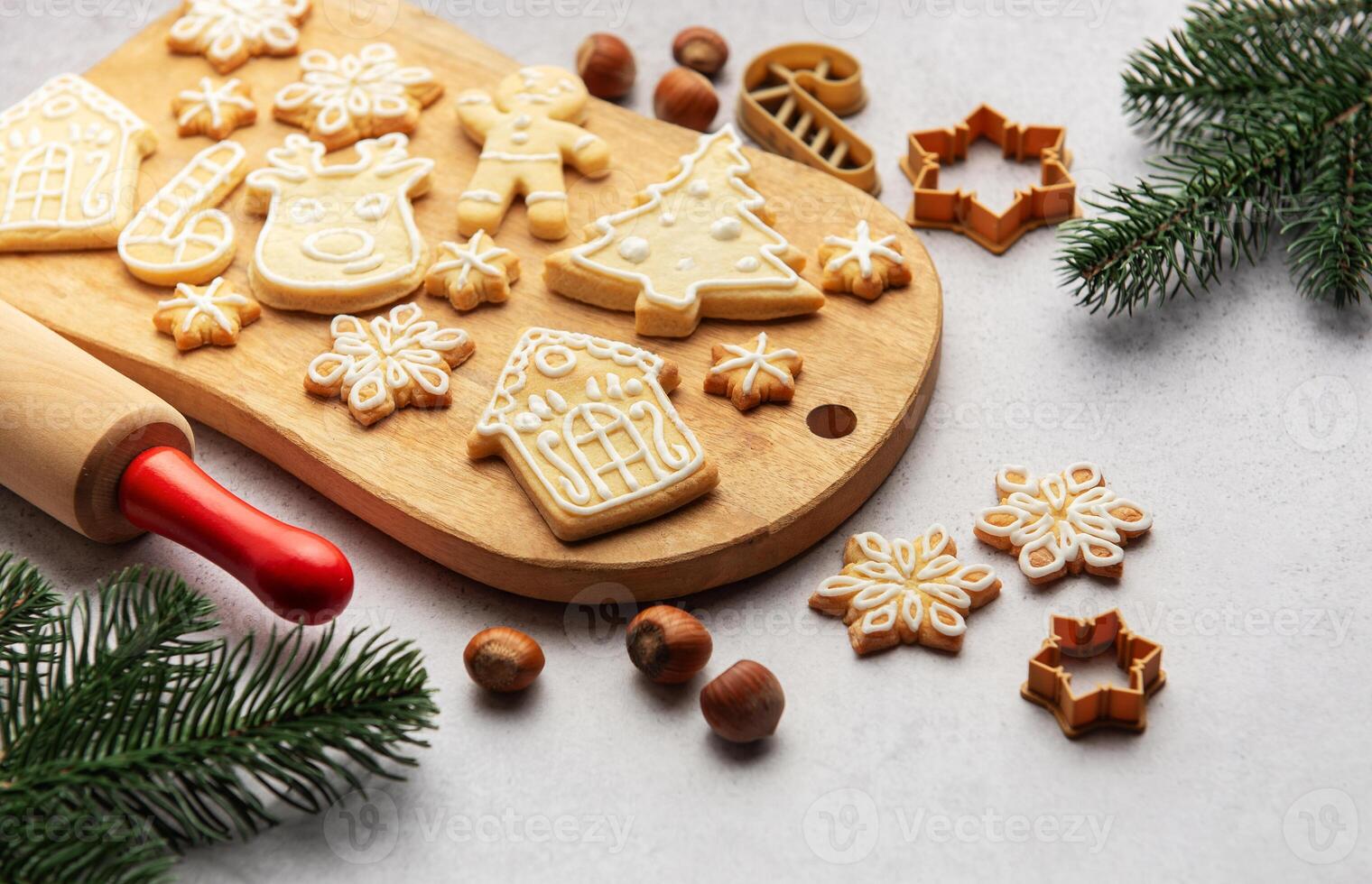 Christmas cookies decorated with icing on wooden board with fir branches and hazelnuts photo