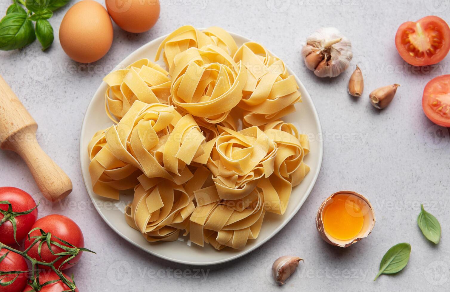 Uncooked pappardelle pasta with ingredients forming frame on table photo