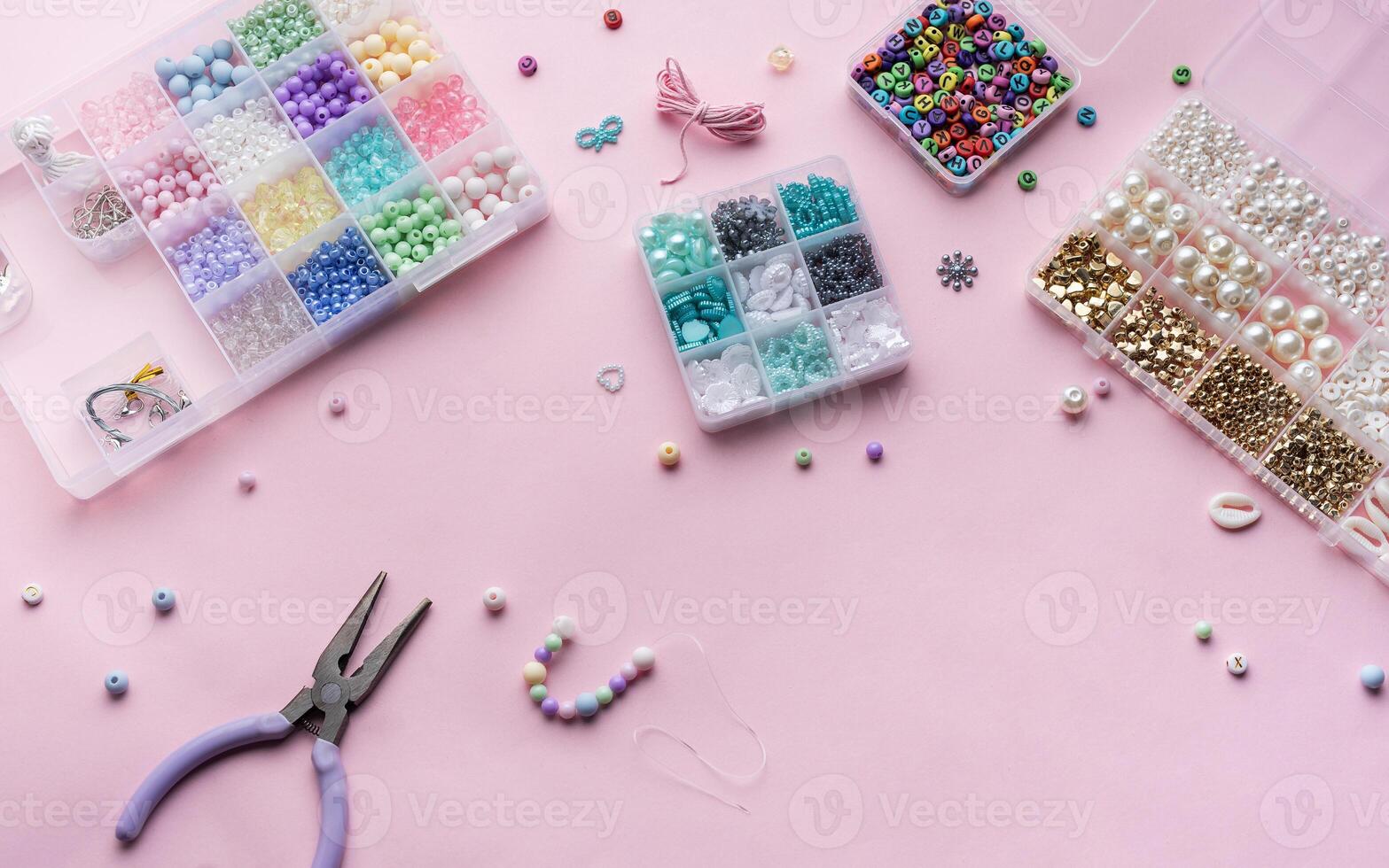 Crafting beautiful jewelry with beads and supplies on a pastel pink surface photo