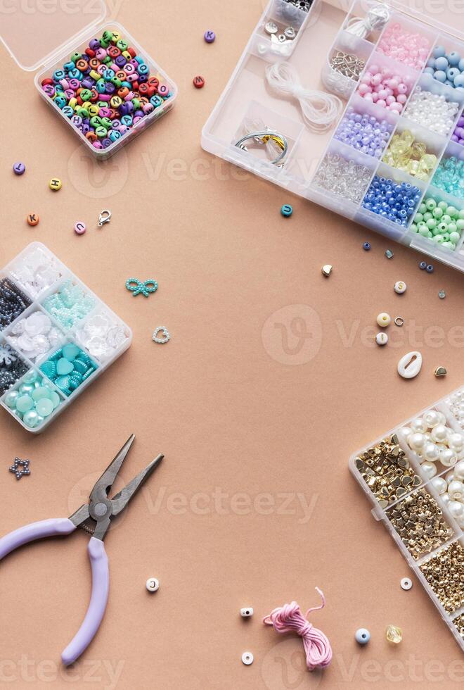 Crafting with colorful beads on a flat workspace with tools and containers in bright daylight photo