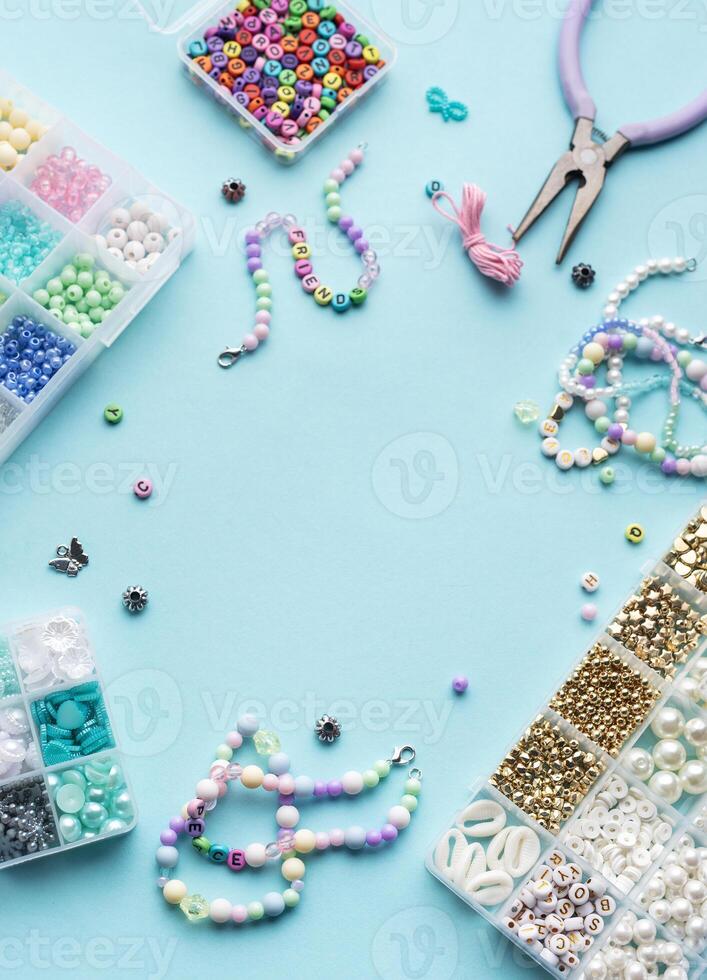Colorful assortment of beads and jewelry-making tools on a blue surface with completed bracelets photo