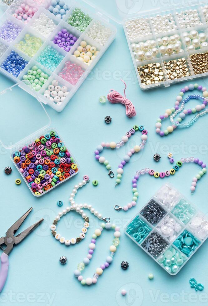 Colorful assortment of beads and jewelry-making tools on a blue surface with completed bracelets photo