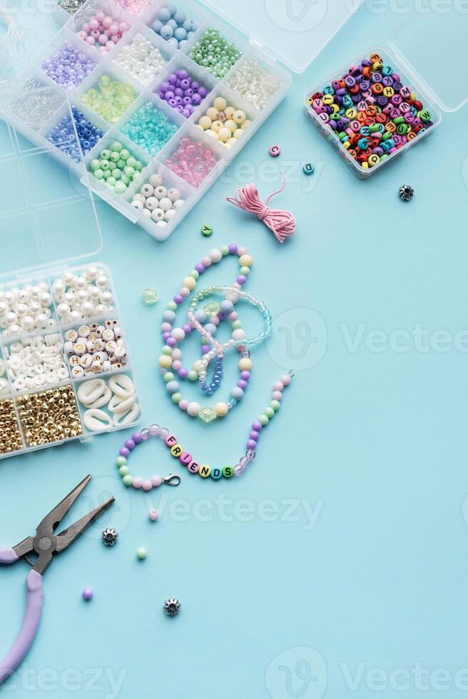 Crafting colorful beaded jewelry on a blue surface with tools and a variety of beads photo