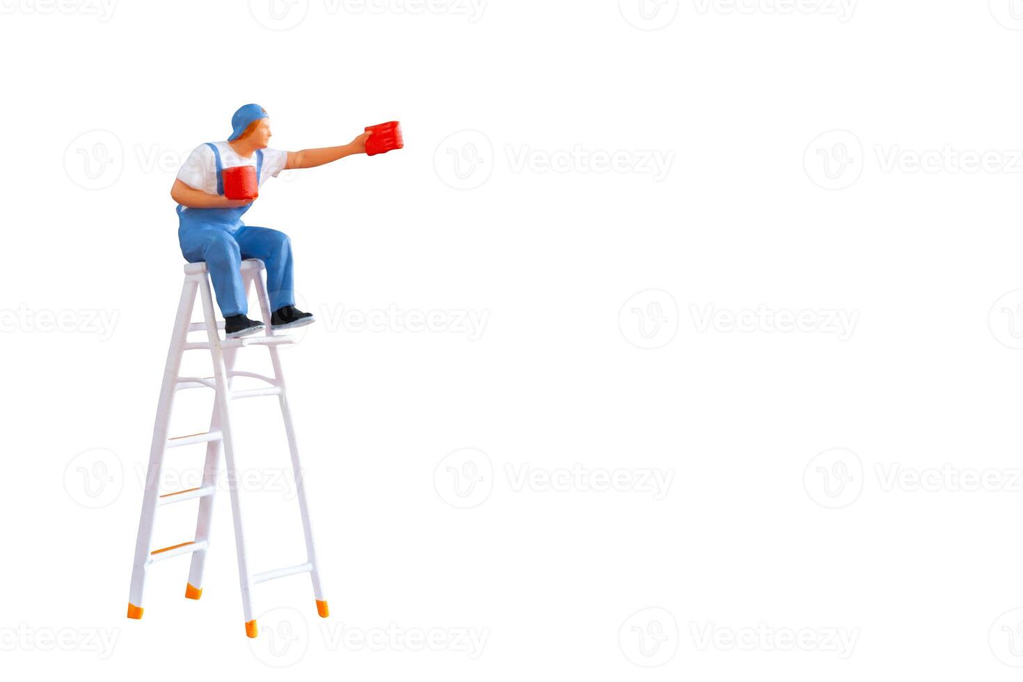 A miniature figurine of a painter seated on a ladder, holding a paint can and brush.isolate on white back ground with clipping path photo
